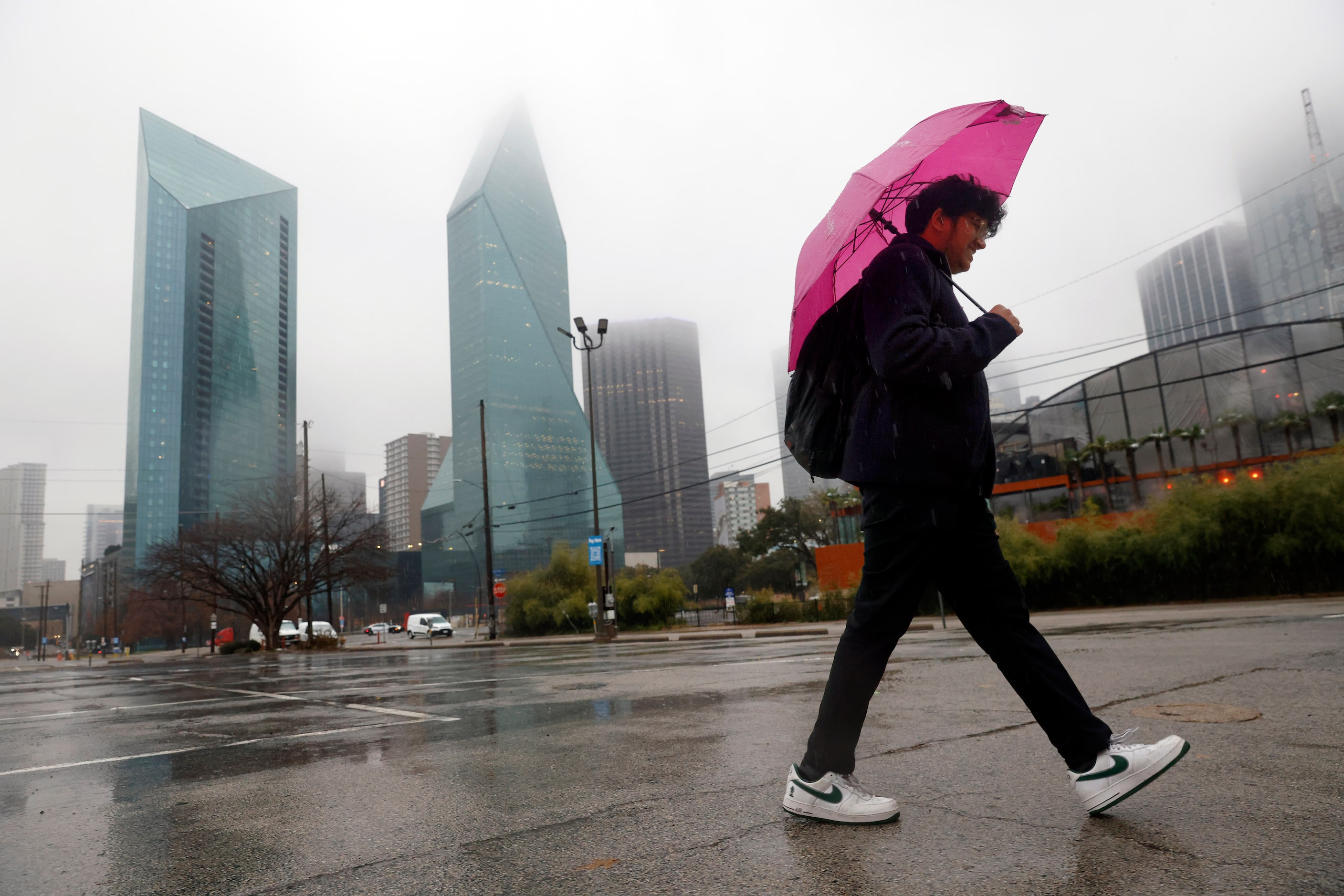 In a steady rain, Akhil Puduru makes his way home from work as he passes Fountain Place in...