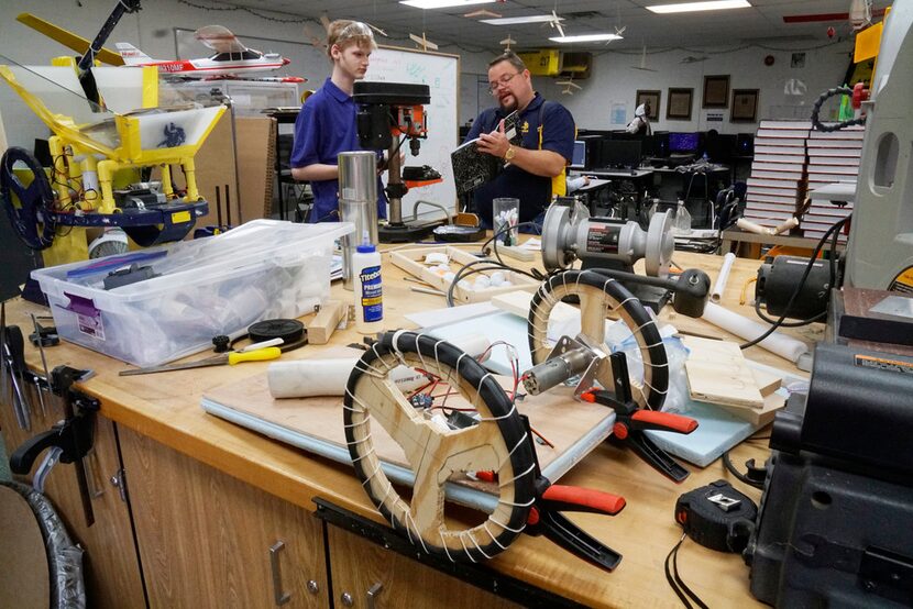 Lamar High robotics team member Aidan Cooper discusses design with his instructor, Erik...