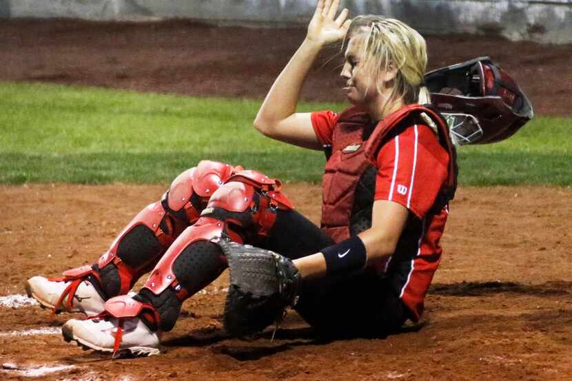 Mansfield catcher Reagan Wright flips her mask off after being dinged by a foul tip in the...