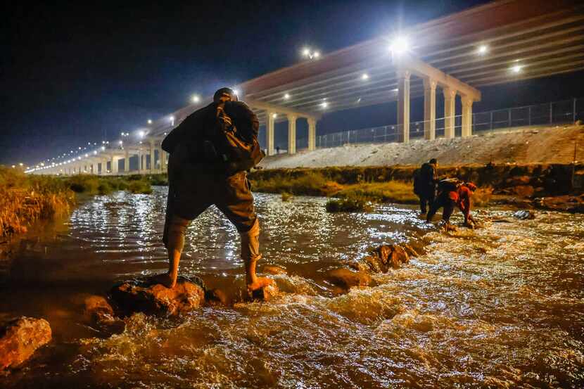 Migrants cross the Rio Grande river and US-Mexico border into El Paso, Texas as seen from...