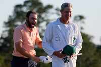 Scottie Scheffler celebrates with his caddie Ted Scott after winning the Masters golf...