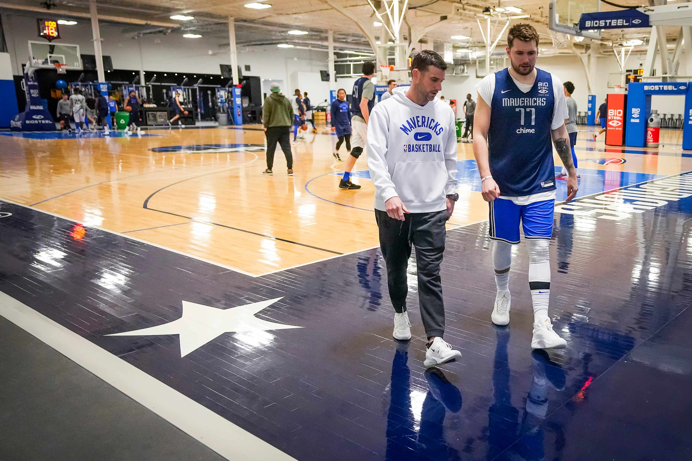 Dallas Mavericks guard Luka Doncic walks to a media availability with Scott Tomlin, vice...