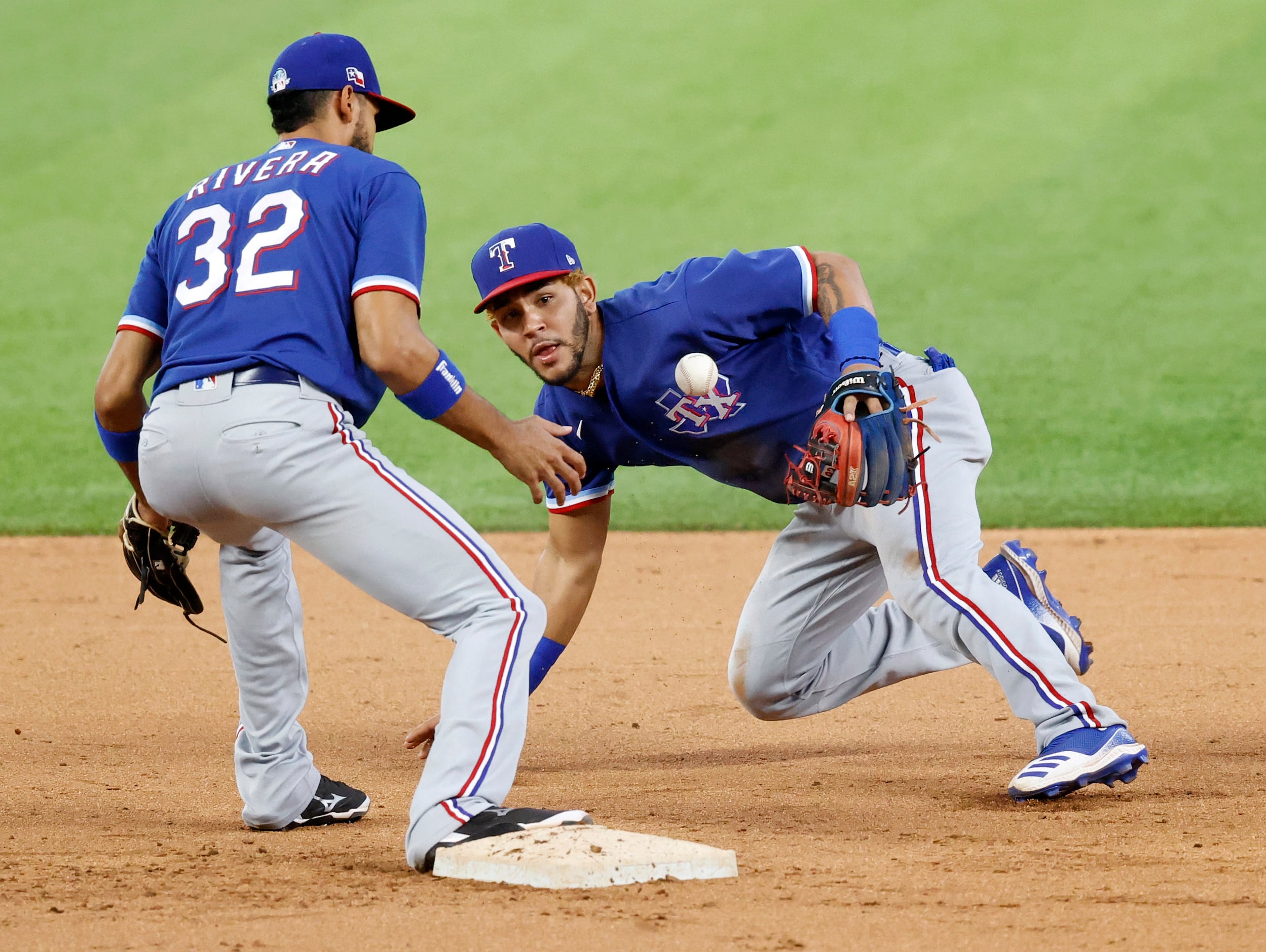 Texas Rangers infielder Anderson Tejeda flips the ball to teammate Yadiel Rivera for the...