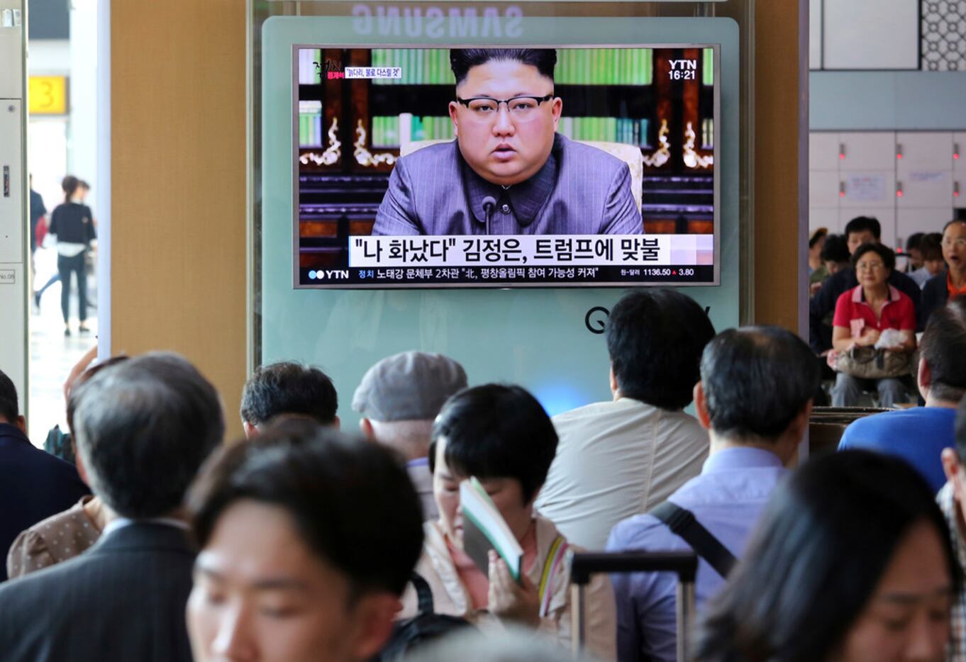 People watch a TV screen showing an image of North Korean leader Kim Jong Un delivering a...