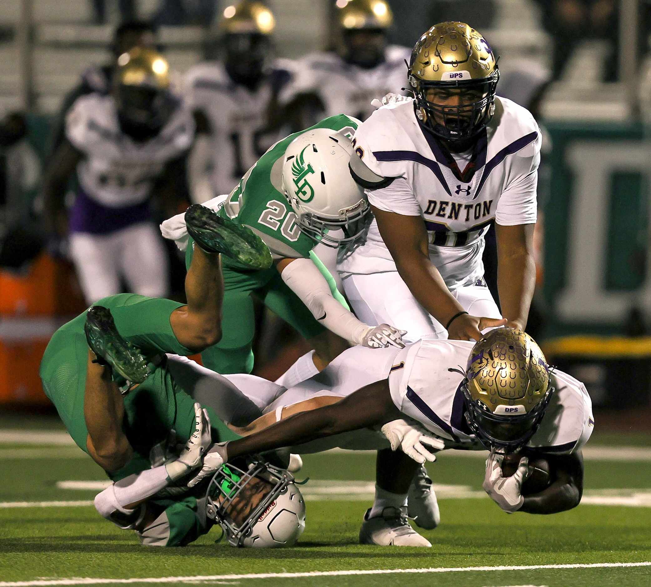 Denton running back Coco Brown (right) gets stopped by Lake Dallas defensive back Xinjin...