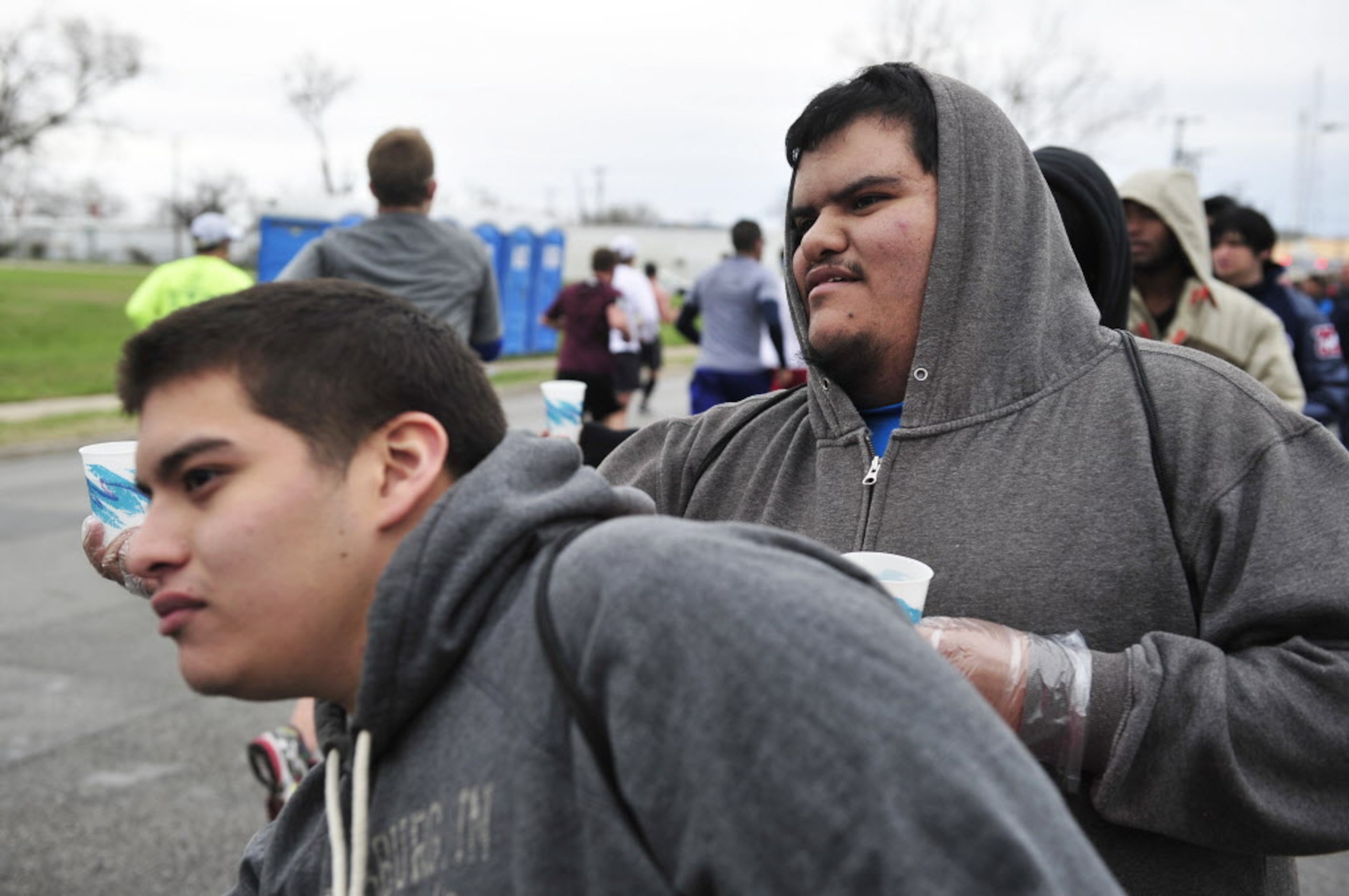 Volunteers Edgar Esparza (right) and Felipe Gaspar (left) pass out water to runners during...