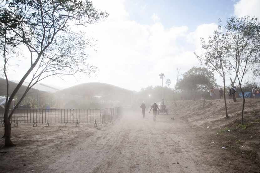 Asylum-seekers walk through a gust of dusty wind in the tent camps in Matamoros, Mexico, on...
