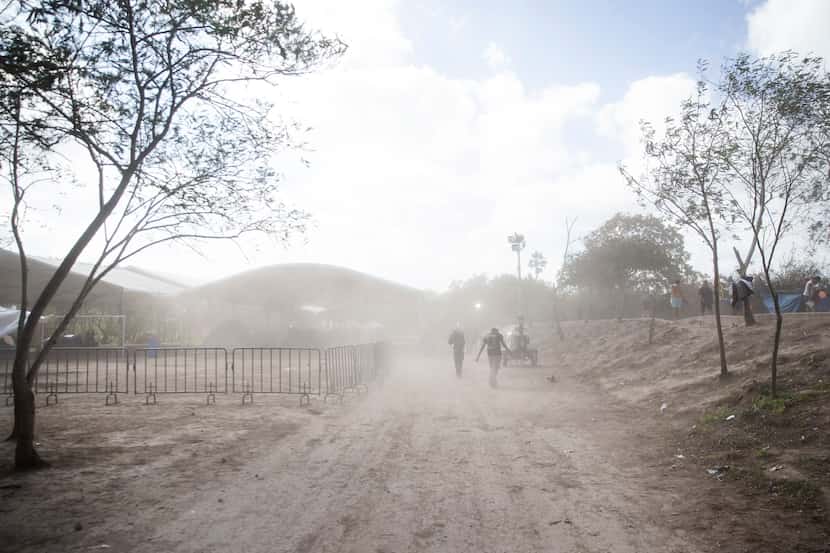 Asylum-seekers walk through a gust of dusty wind in the tent camps in Matamoros, Mexico, on...