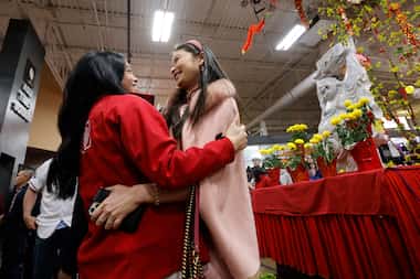 Michelle Tran, Vietnamese descendant, of Las Colinas, left, greets her friend June Loh,...