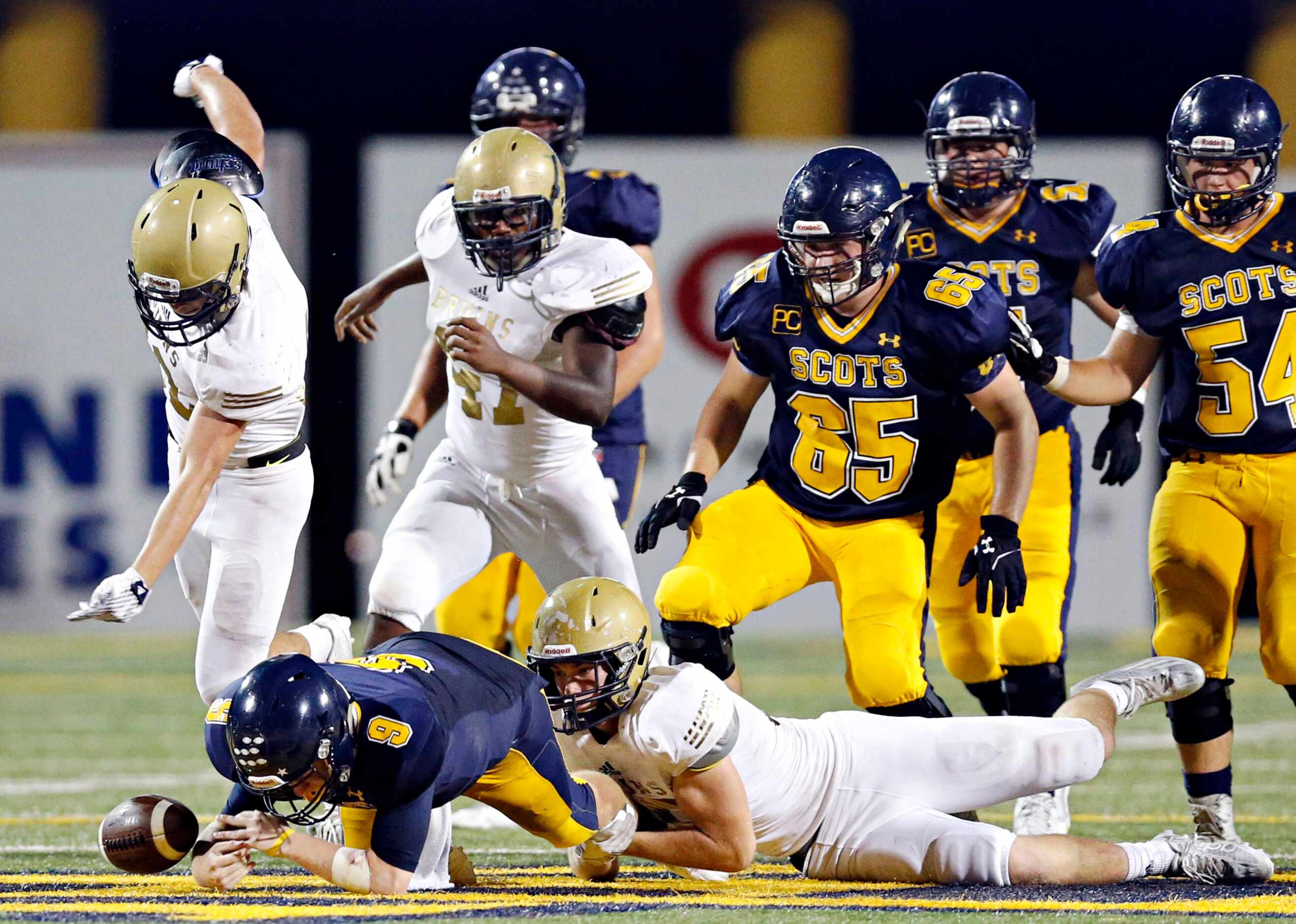 Highland Park quarterback Henry Allen (9) fumbles the ball as he is brought down by...