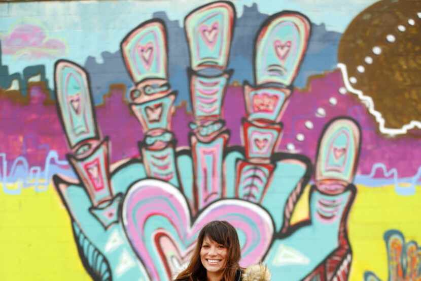 Artist Lesli Marshall poses in front of her mural Cosmic Journey. The piece, on the back...