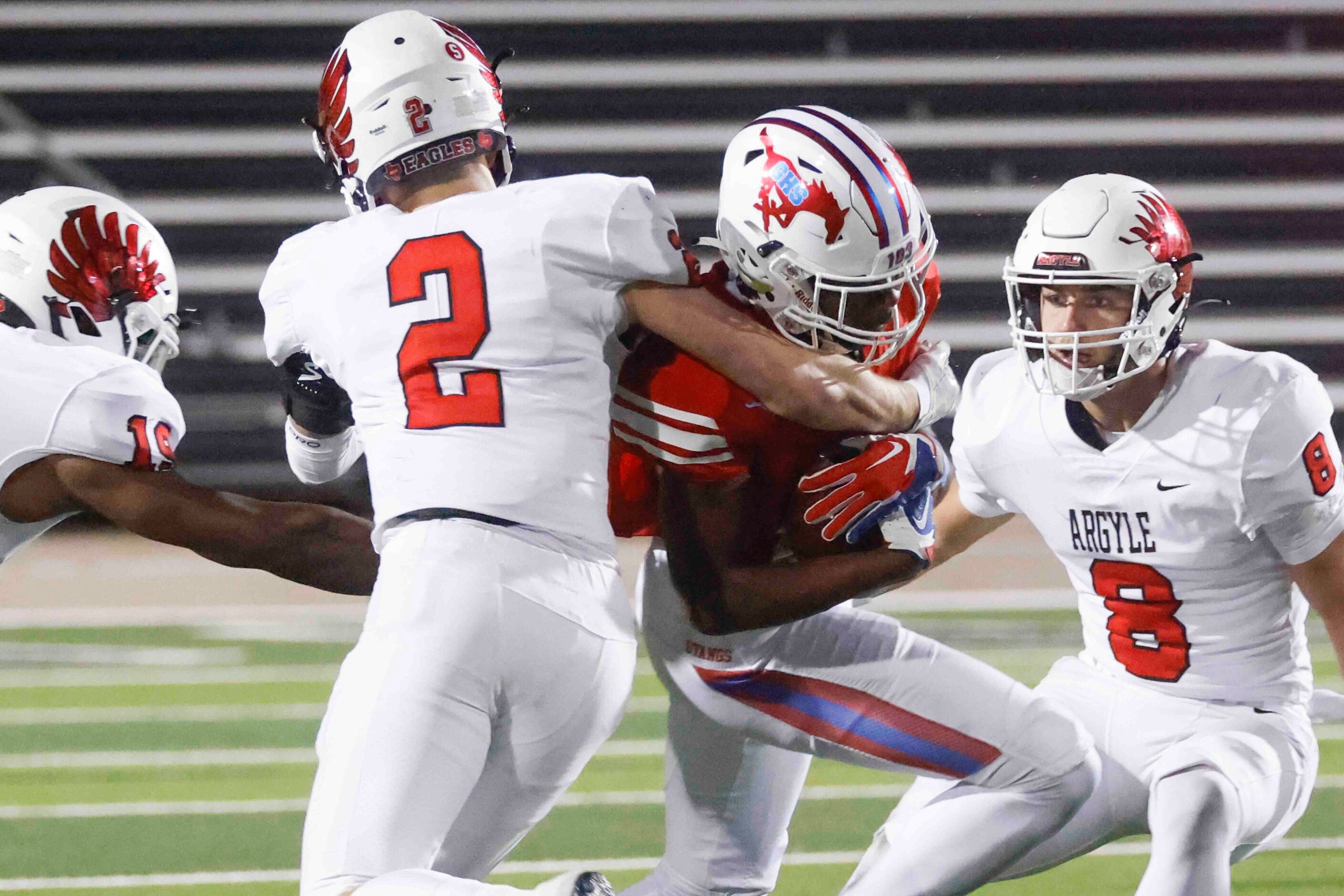 Grapevine High’s Derrius Burns (2), center, gets tackled by Argyle High’s Dax Horany (2),...