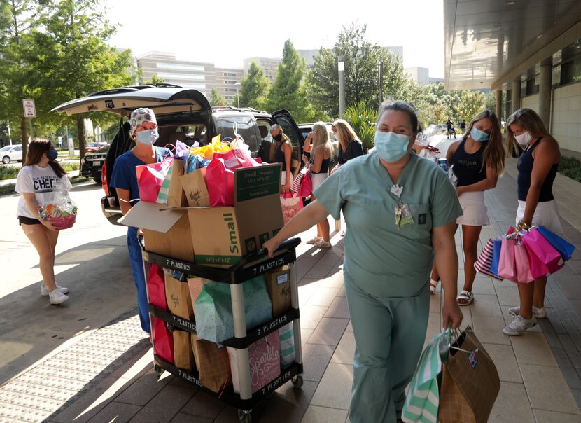 Kelly Jenkins (left) and Elizabeth Salazar move a cart full of gift bags delivered by...