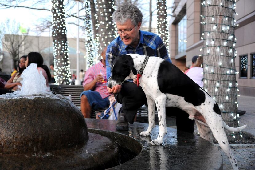 Daniel Tanbein lets his furry friend Ahshun get a drink from the fountain during the annual...
