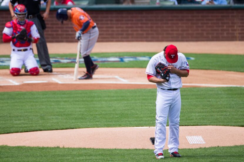 Rangers starting pitcher Derek Holland pauses behind the mound in the first inning. (Smiley...