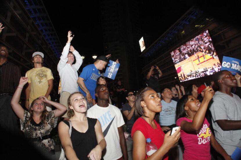 Dallas Mavs fans watch the final seconds of the championship game on the screens outside of...