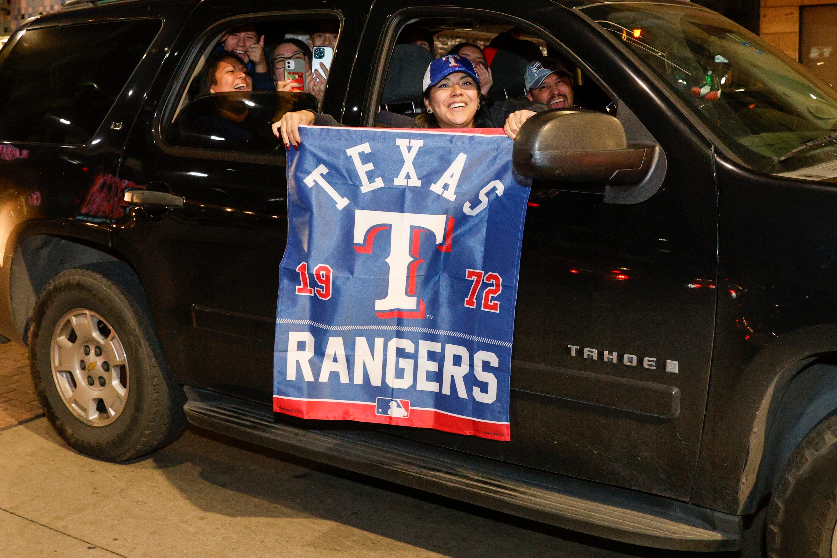 A woman hangs a Texas Rangers flag out her car’s window on Main Street after the Texas...