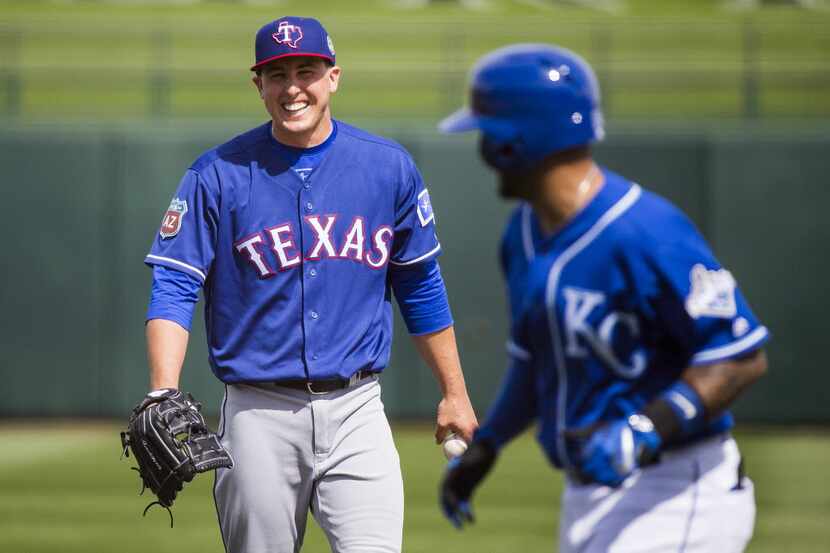 Texas Rangers pitcher Derek Holland laughs at something said by Kansas City Royals infielder...