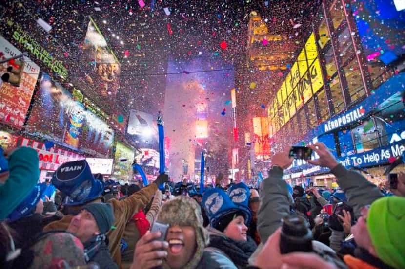 
Revelers cheer under falling confetti during the 2014 New Year’s Eve celebrations in Times...