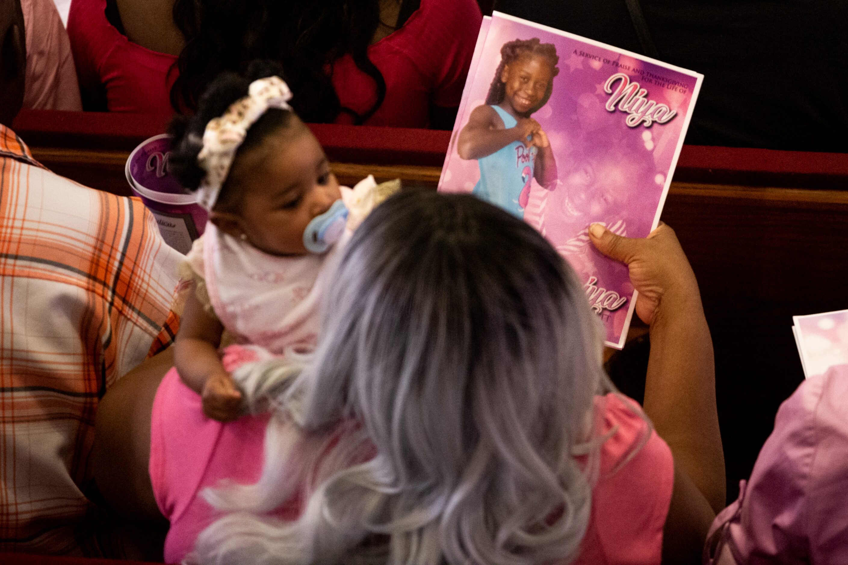 A woman holds the program for BrandoniyaÕs funeral. It features a photo of the 9-year-old...