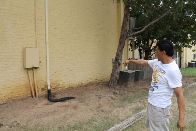 Francisco Gonzalez points to the gutter behind his building which has caused some water...