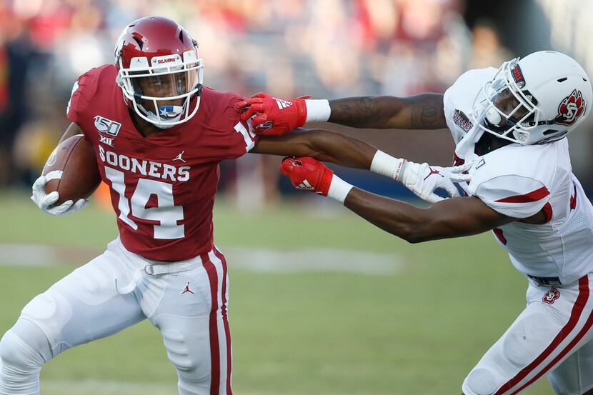 Oklahoma wide receiver Charleston Rambo (14) fights off a tackle from South Dakota defender...