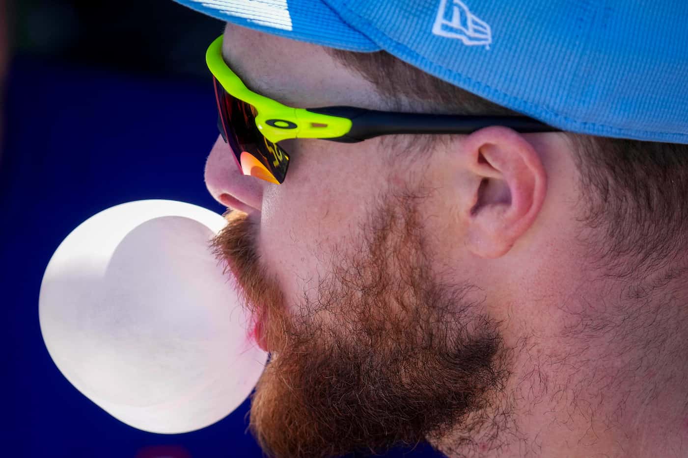 Texas Rangers infielder Jared Walsh blows a bubble in the dugout before a spring training...