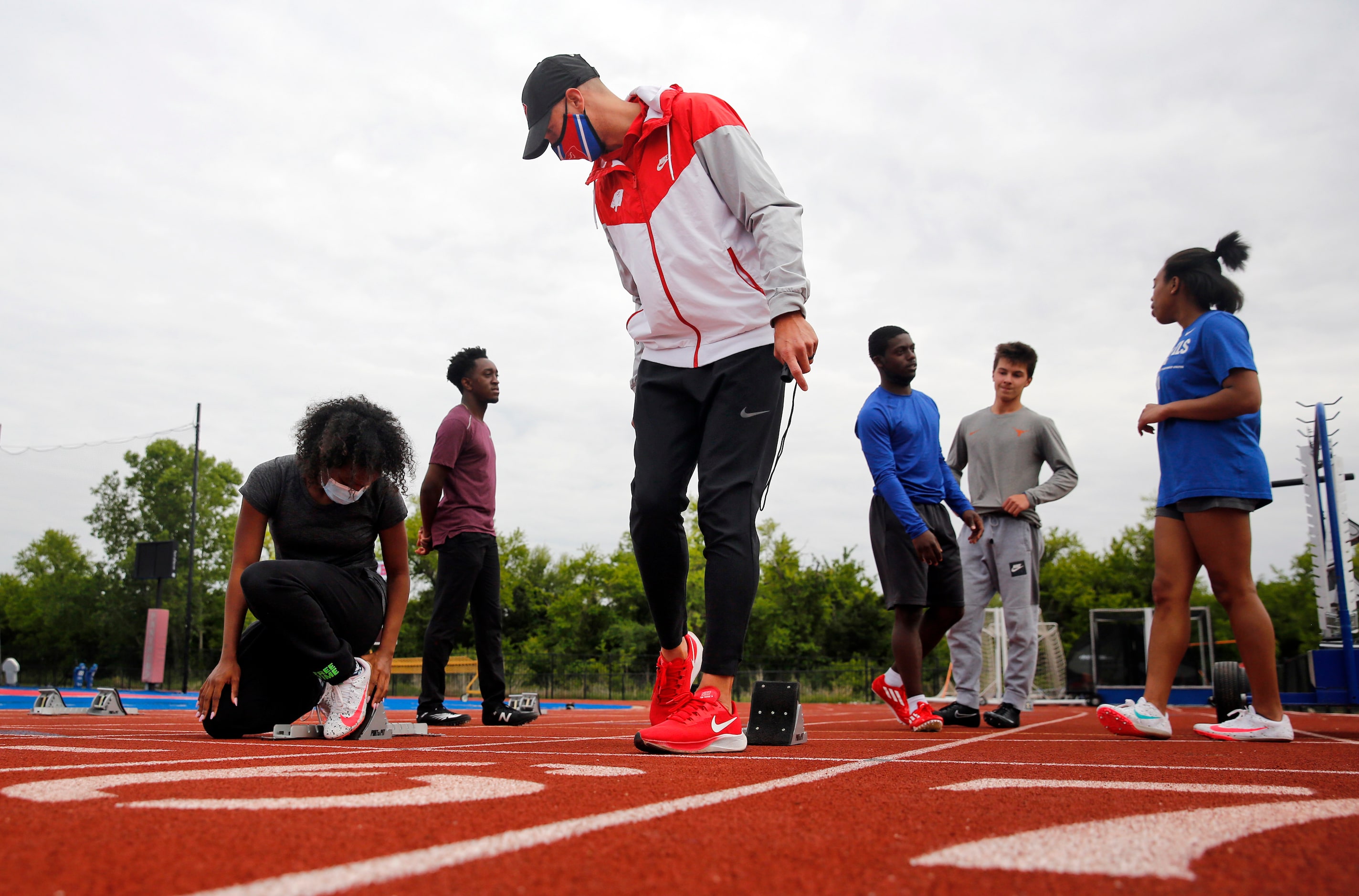 Parish Episcopal head track coach Jeremy Wariner shows start block technique to sophomore...