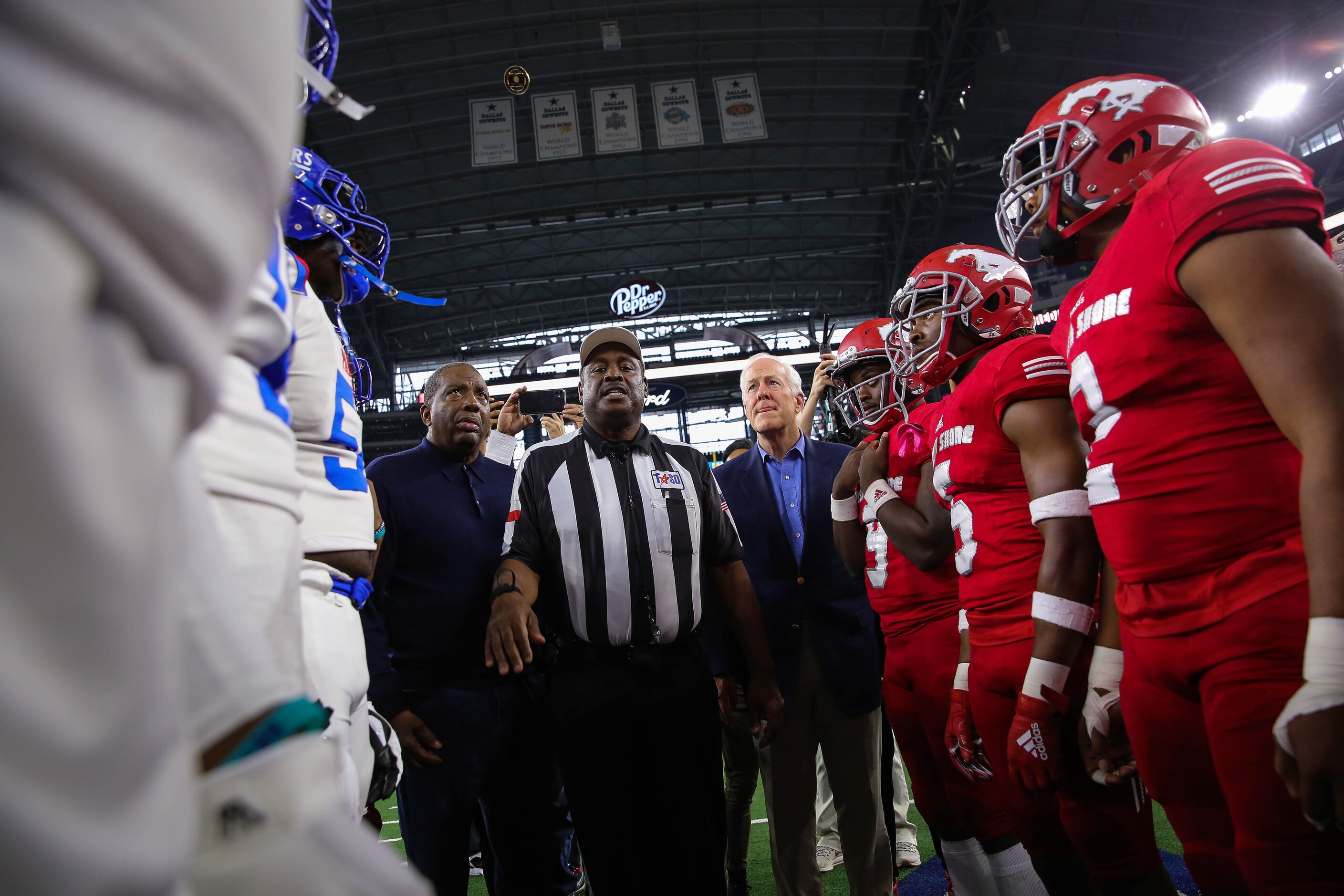 State Sen. Royce West (center left) and U.S. Sen. John Cornyn (center right) watch the coin...