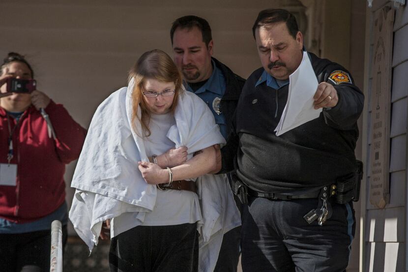Sara Packer, center, handcuffed, the adoptive mother of Grace Packer, was led out of...
