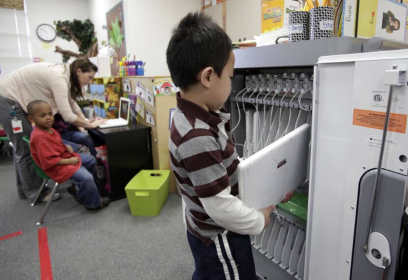 Jason Luu, 5, returns a laptop to the COW (computer on wheels) cart at Beaver Elementary in...