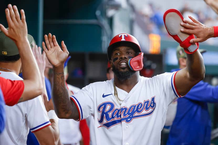 Texas Rangers right fielder Adolis Garcia (left) reaches the home plate, scoring from a...