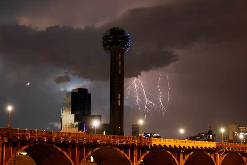 Lighting from a passing storm strikes in the distance behind Reunion Tower in downtown Dallas.