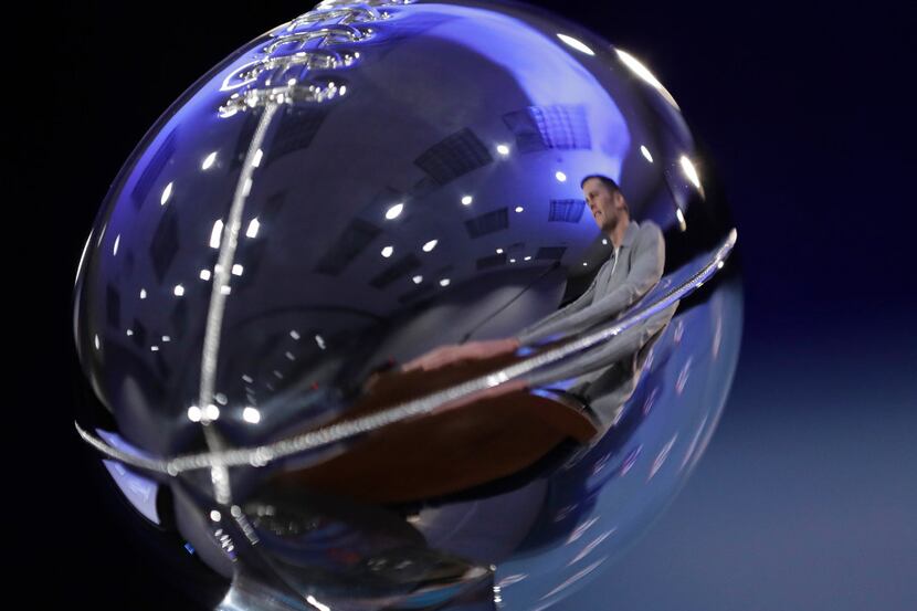 New England Patriots quarterback Tom Brady is reflected in the Lombardi Trophy during a news...