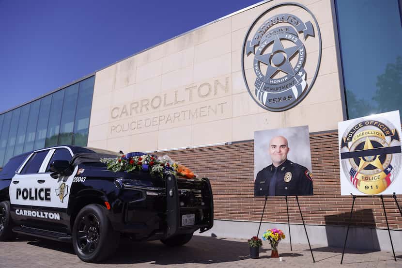 A line of flowers lay atop a police vehicle in front of the Carrollton Police Department...