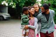 African American mother and father carry their children and smile.