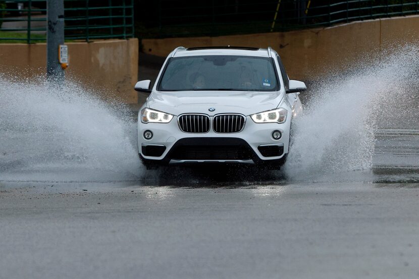 A car splashes through standing water after an afternoon thunderstorm at Churchill Way and...