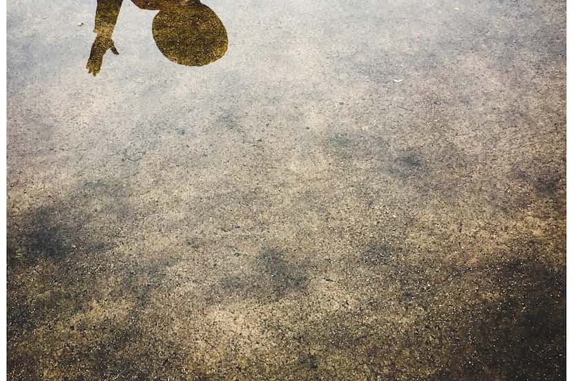 Big Tex is reflected in a puddles left by a morning rain showers create reflections during...
