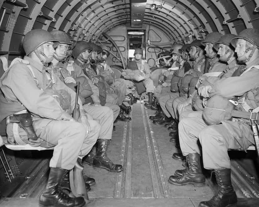 American paratroopers sit inside a military plane as they soar over the English Channel en...