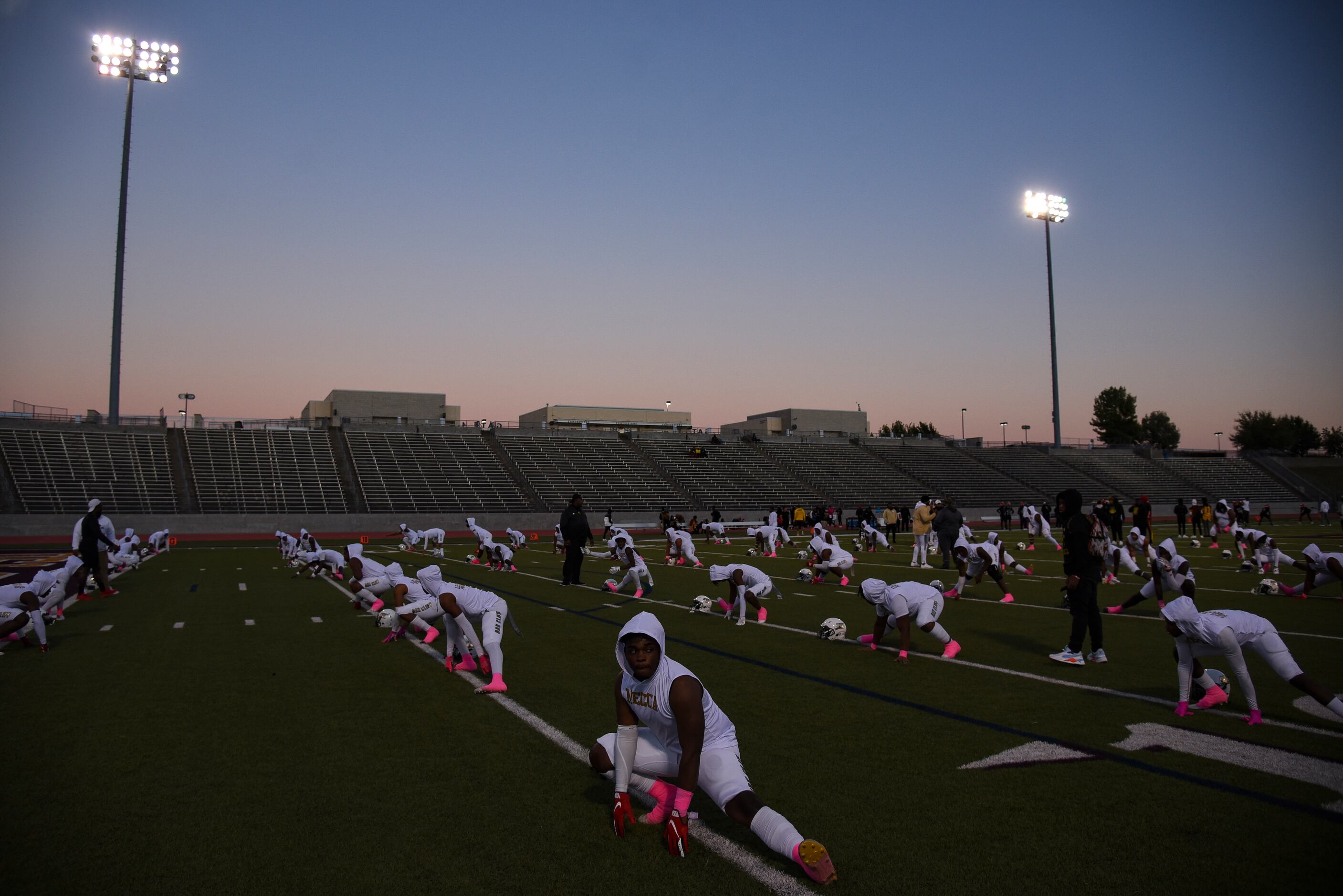 South Oak Cliff players stretch as the sun sets before the start of the District 6-5A...