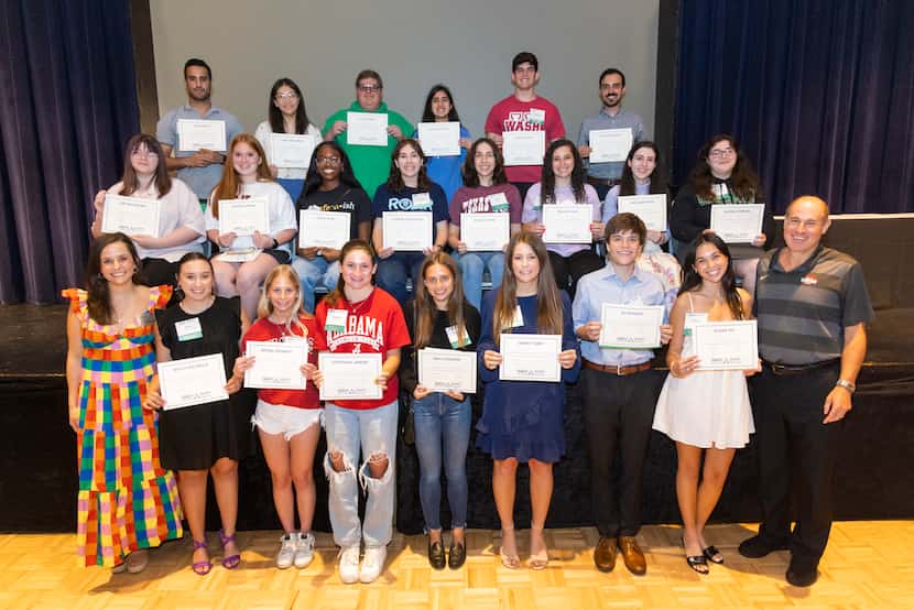Students ranging from elementary to college age stand with certificates showing the...