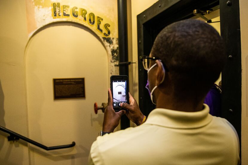 Dannion McLendon takes a photo of the historical marker and sign that reads “NEGROES” at the...