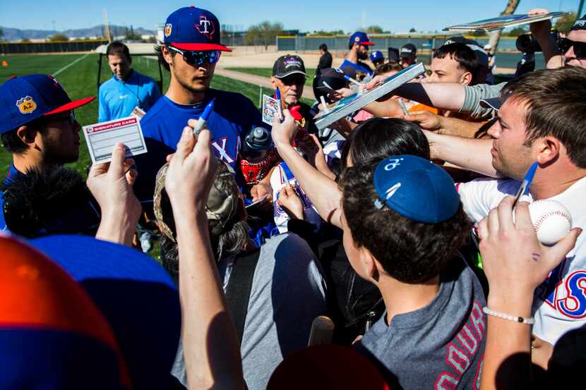 Texas Rangers starting pitcher Yu Darvish (11) signs autographs for fans during a spring...
