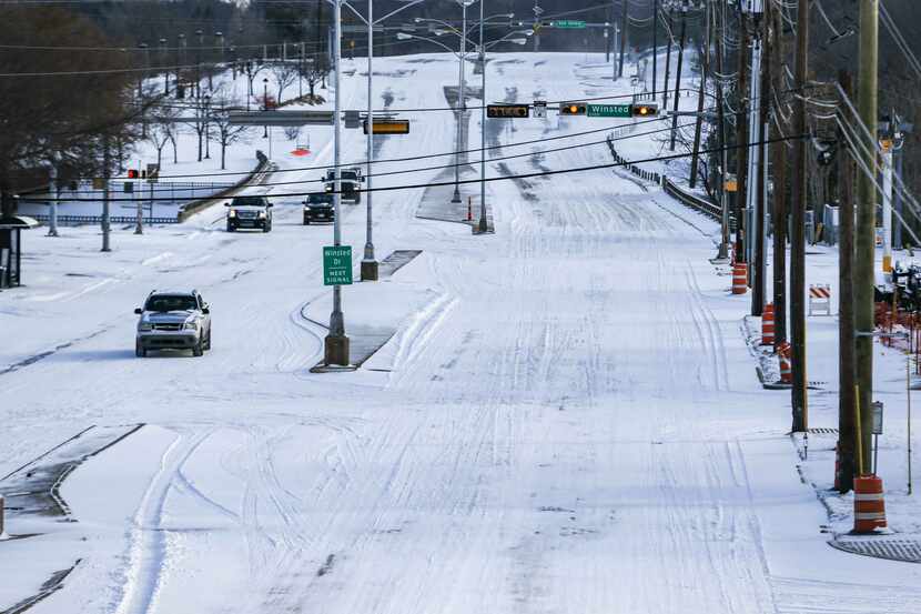 Vehicles crawl along Garland Road near White Rock Lake in Dallas on Monday as freezing...