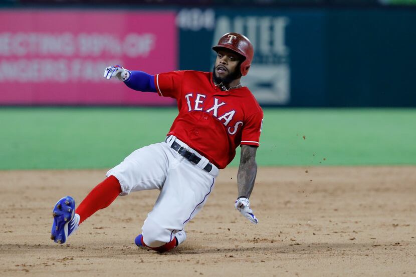 Texas Rangers' Delino DeShields slides into third with a triple on a pitch from Minnesota...
