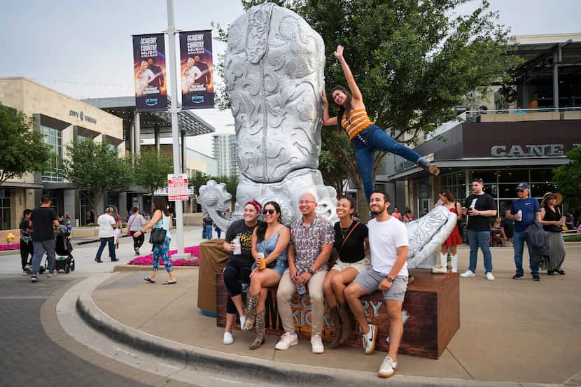 Folks posed for a photo with a large cowboy boot at the ACM Country Kickoff fan festival at...