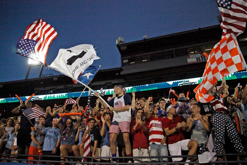 Nathan Ciatti (center), 18, a senior at Wakeland High School, waves patriotic flags as the...
