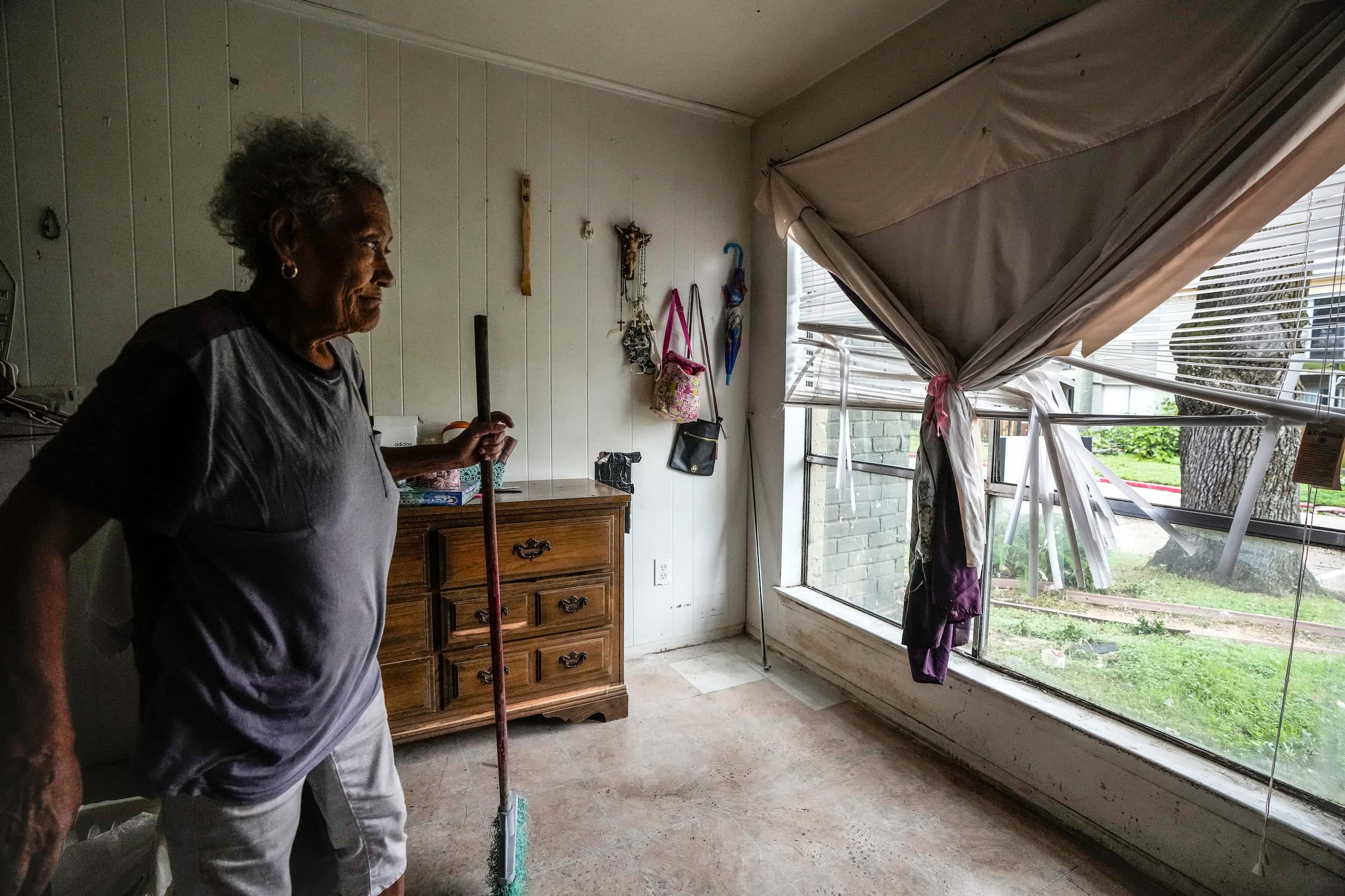 Maria Castillo cleans up water and debris from a broken window at her apartment in the...