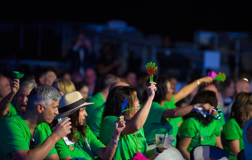 Audience of people dressed in green clapping and cheering.