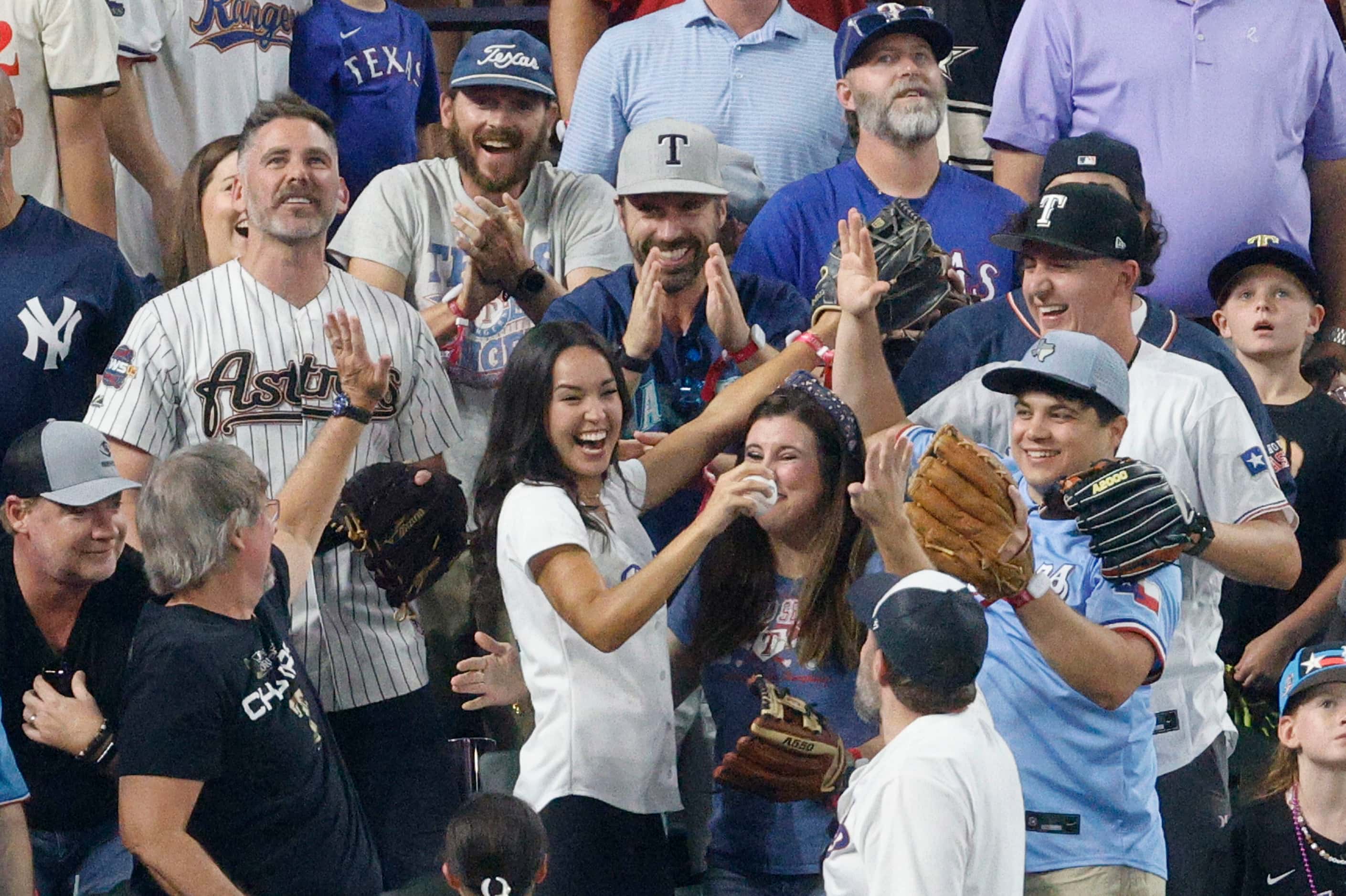 A fan shows a ball after she caught a ball hit by American League's Adolis Garcia, of the...